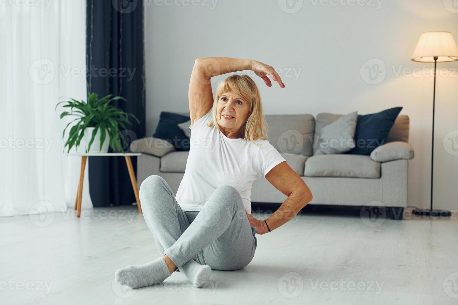 fazendo exercícios de condicionamento físico. mulher sênior com cabelo loiro está em casa foto