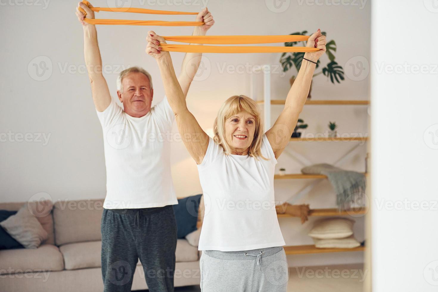 fazendo exercícios de alongamento e fitness. homem e mulher sênior estão juntos em casa foto