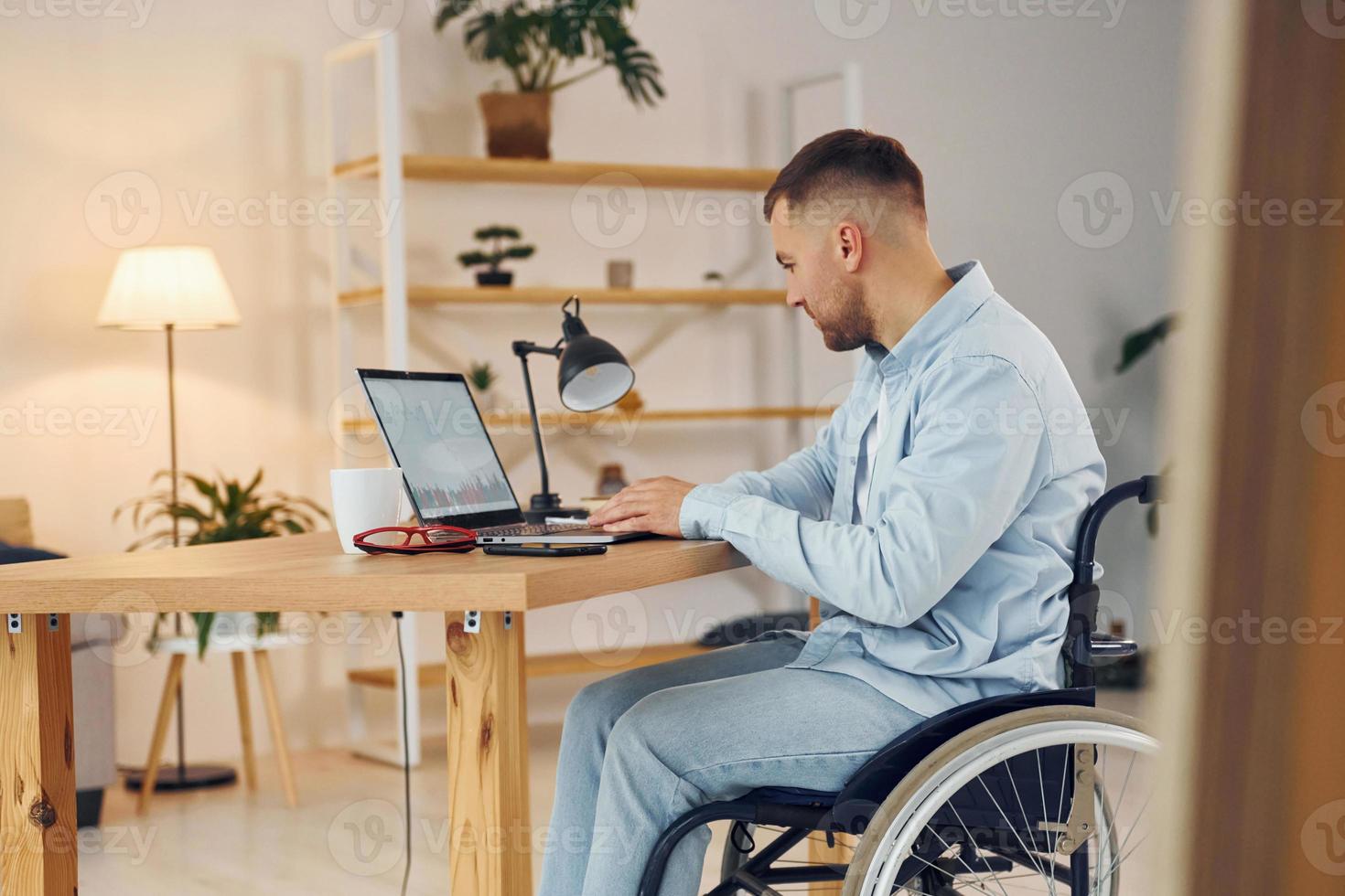 trabalhador de negócios. homem com deficiência em cadeira de rodas está em casa foto