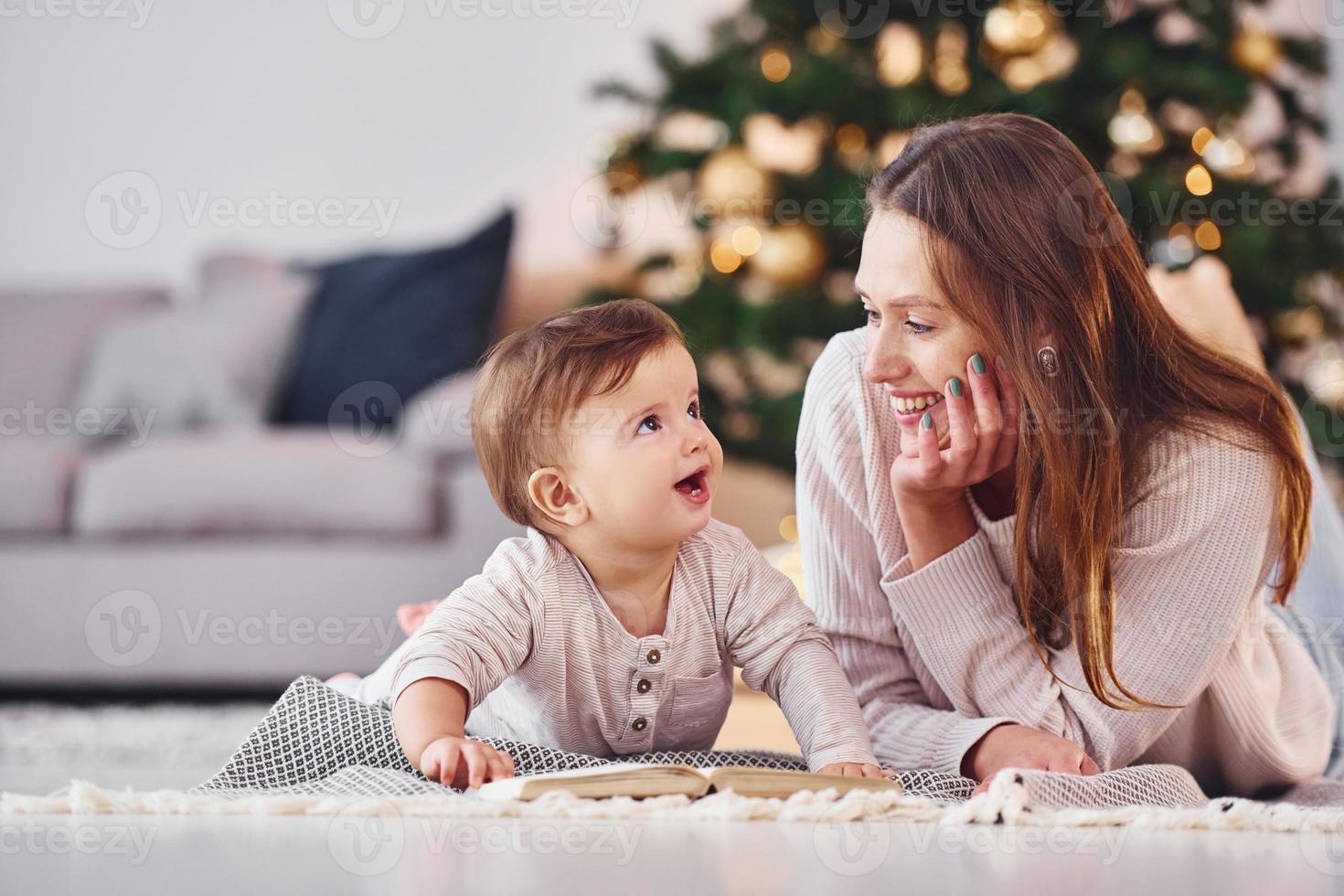 com o livro que está no chão. mãe com sua filha está dentro de casa juntos foto