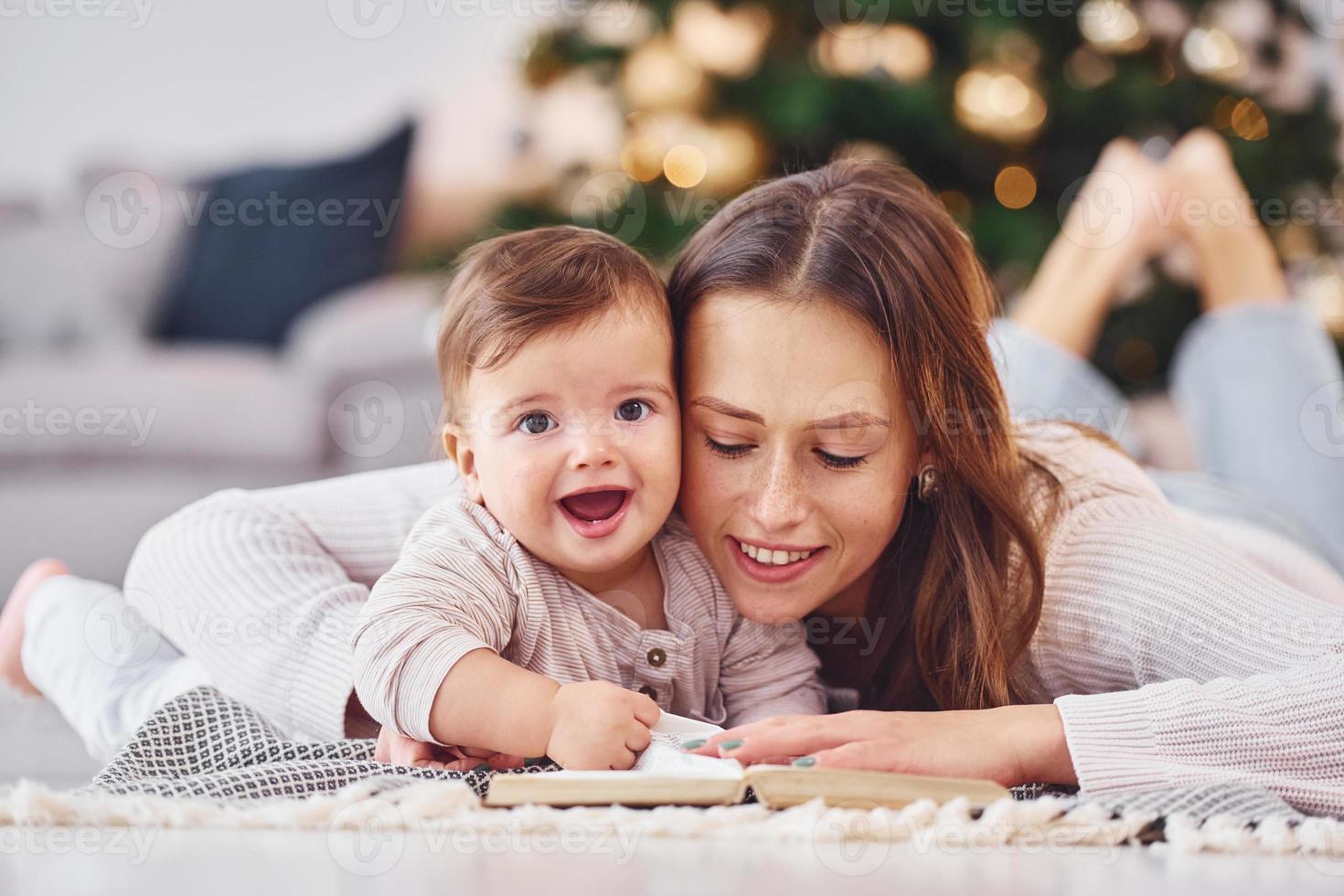 com o livro que está no chão. mãe com sua filha está dentro de casa juntos foto