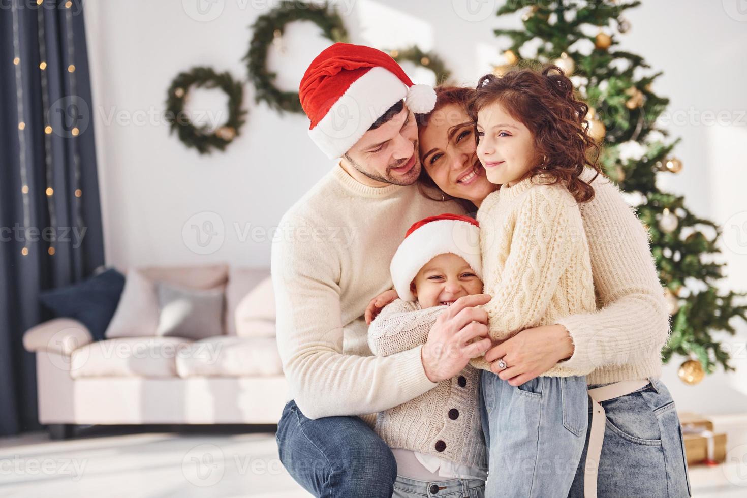 em chapéus de natal. família comemorando o ano novo com seus filhos em casa foto