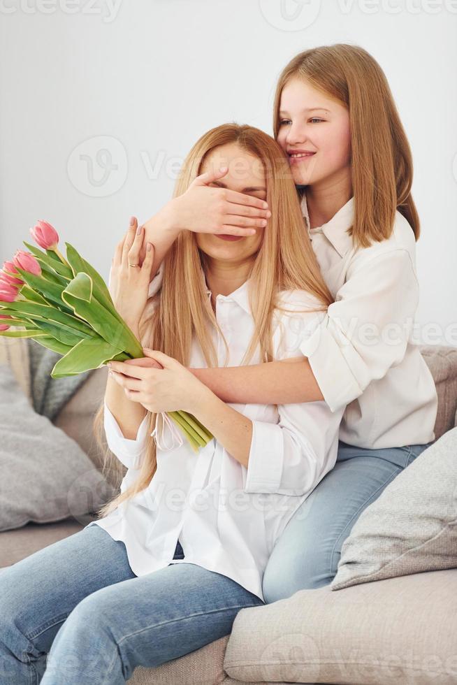 flores no feriado. jovem mãe com sua filha está em casa durante o dia foto