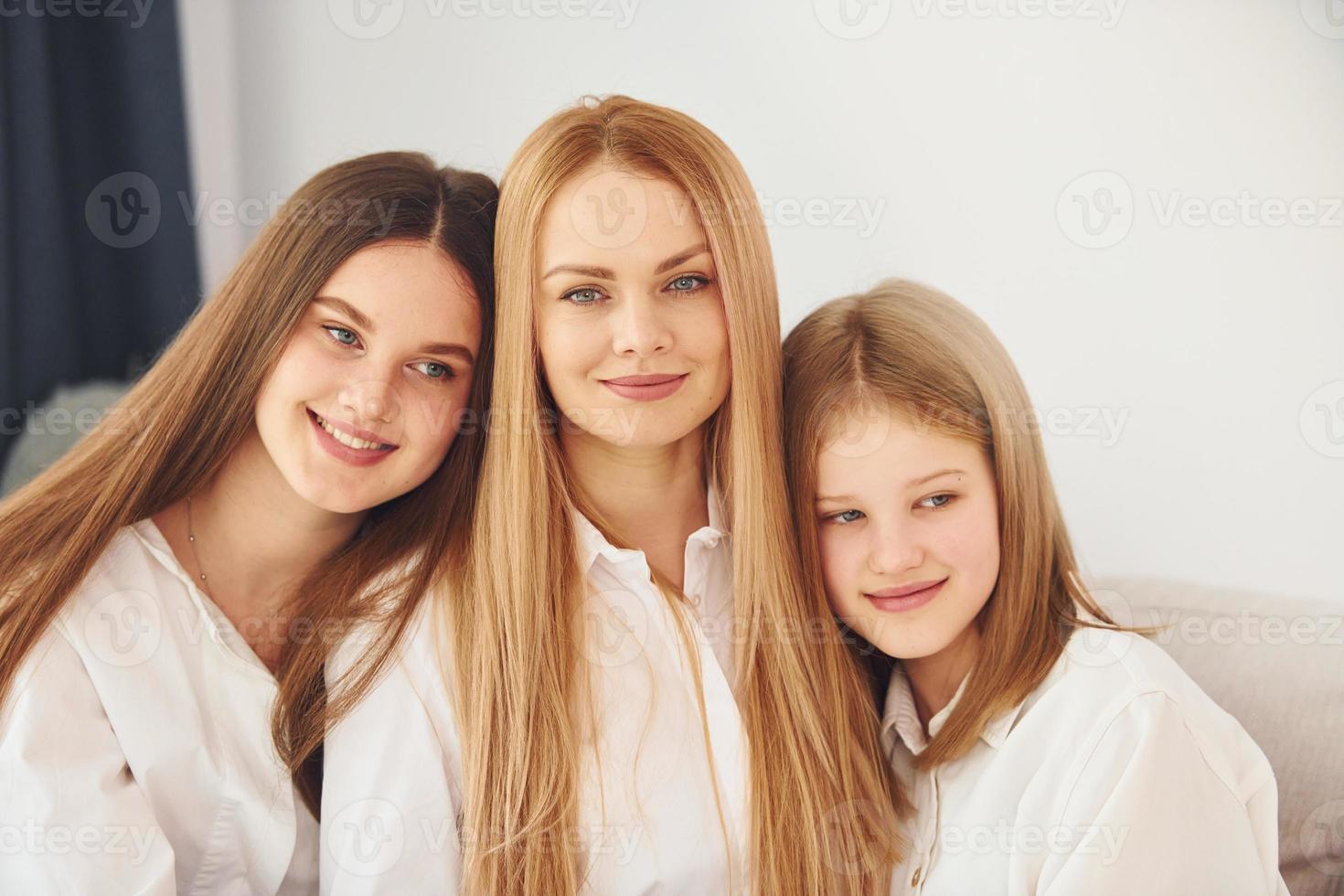 sentado no sofá. jovem mãe com suas duas filhas em casa durante o dia foto