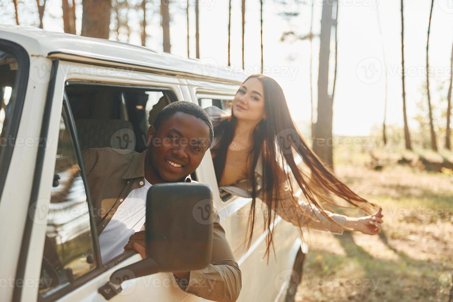 sentado no carro. jovem casal está viajando na floresta durante o dia juntos foto