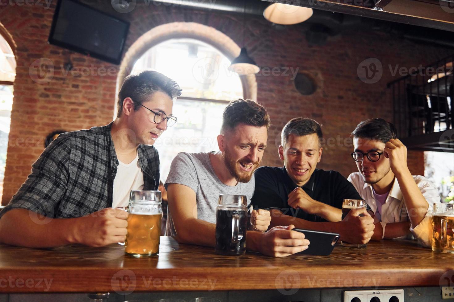 vista lateral de amigos com cerveja. pessoas em roupas casuais sentadas no pub foto