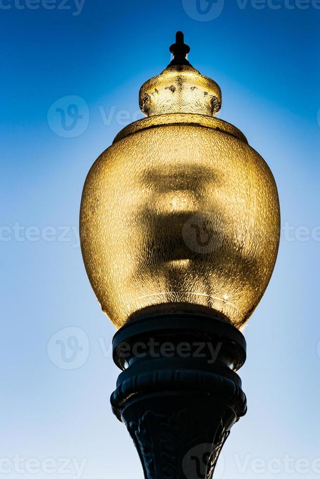 cabeça de lâmpada de rua de vidro em um poste de ferro fundido foto