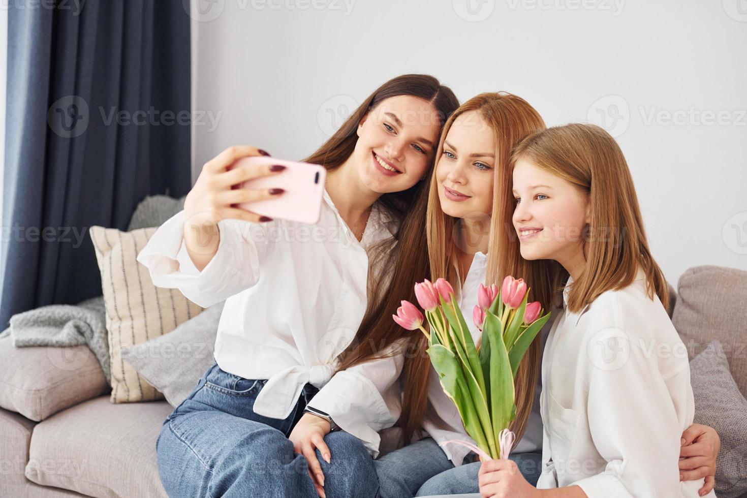 sentado com presentes. jovem mãe com suas duas filhas em casa durante o dia foto
