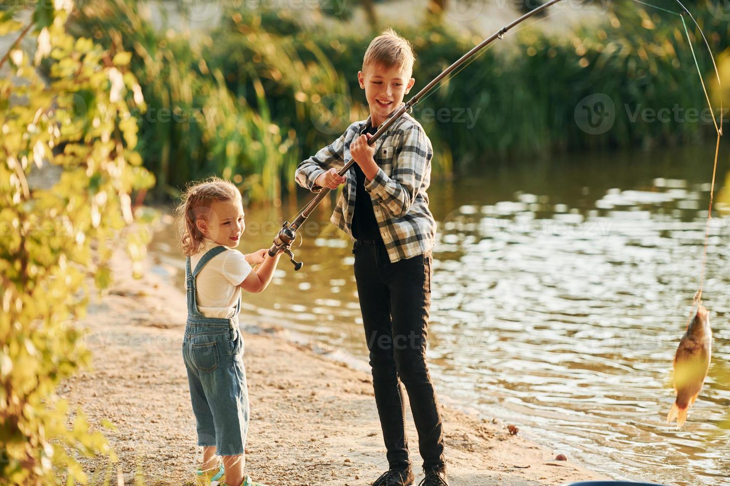 se divertindo. menino com sua irmã na pesca ao ar livre no verão juntos foto