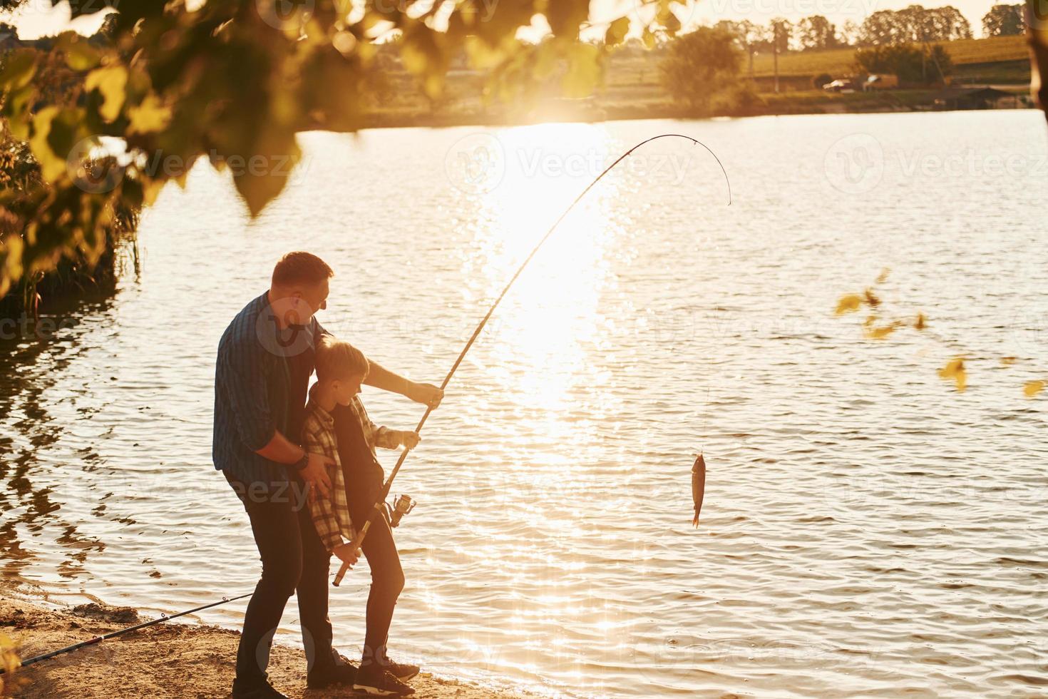 com captura. pai e filho pescando juntos ao ar livre no verão foto