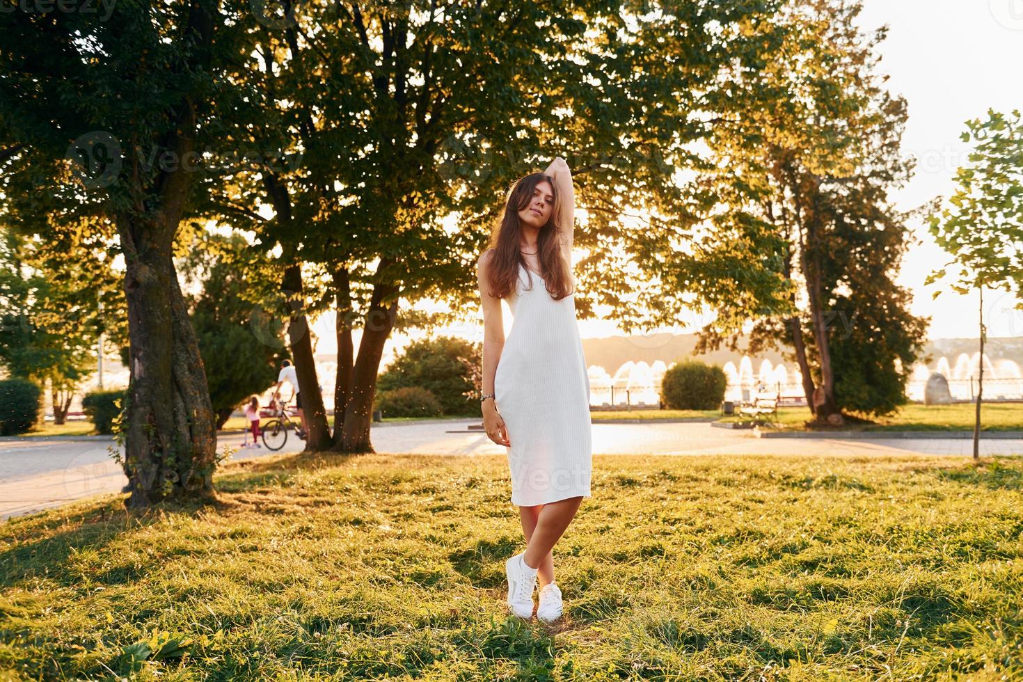 em vestido branco. mulher em pé no parque outono. lindo sol foto