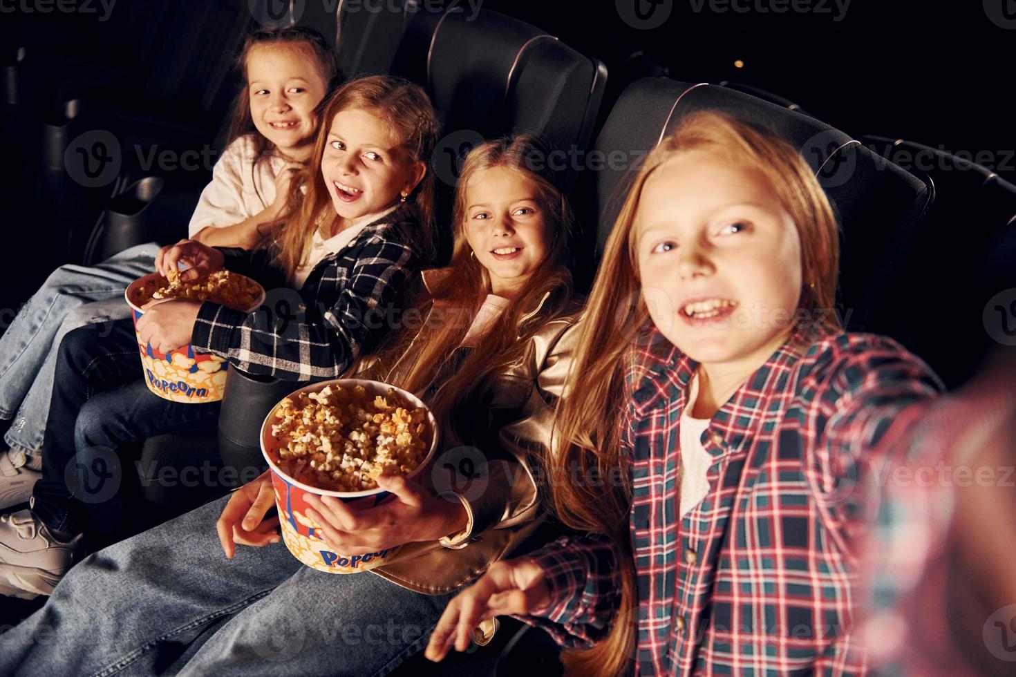 em quarto escuro. grupo de crianças sentadas no cinema e assistindo filme juntos foto