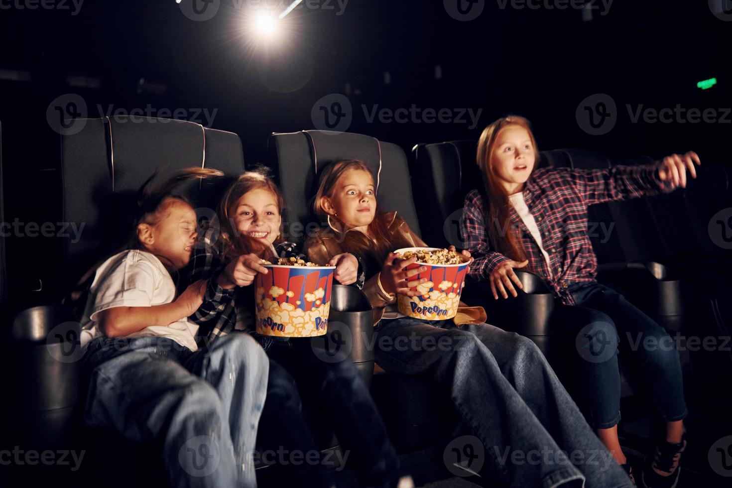 sentado nos assentos pretos. grupo de crianças sentadas no cinema e assistindo filme juntos foto