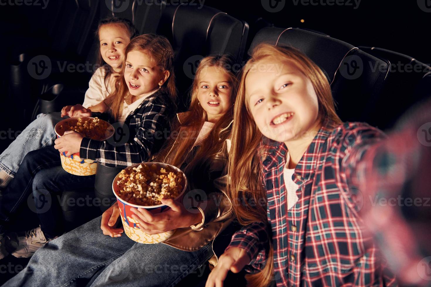 em quarto escuro. grupo de crianças sentadas no cinema e assistindo filme juntos foto