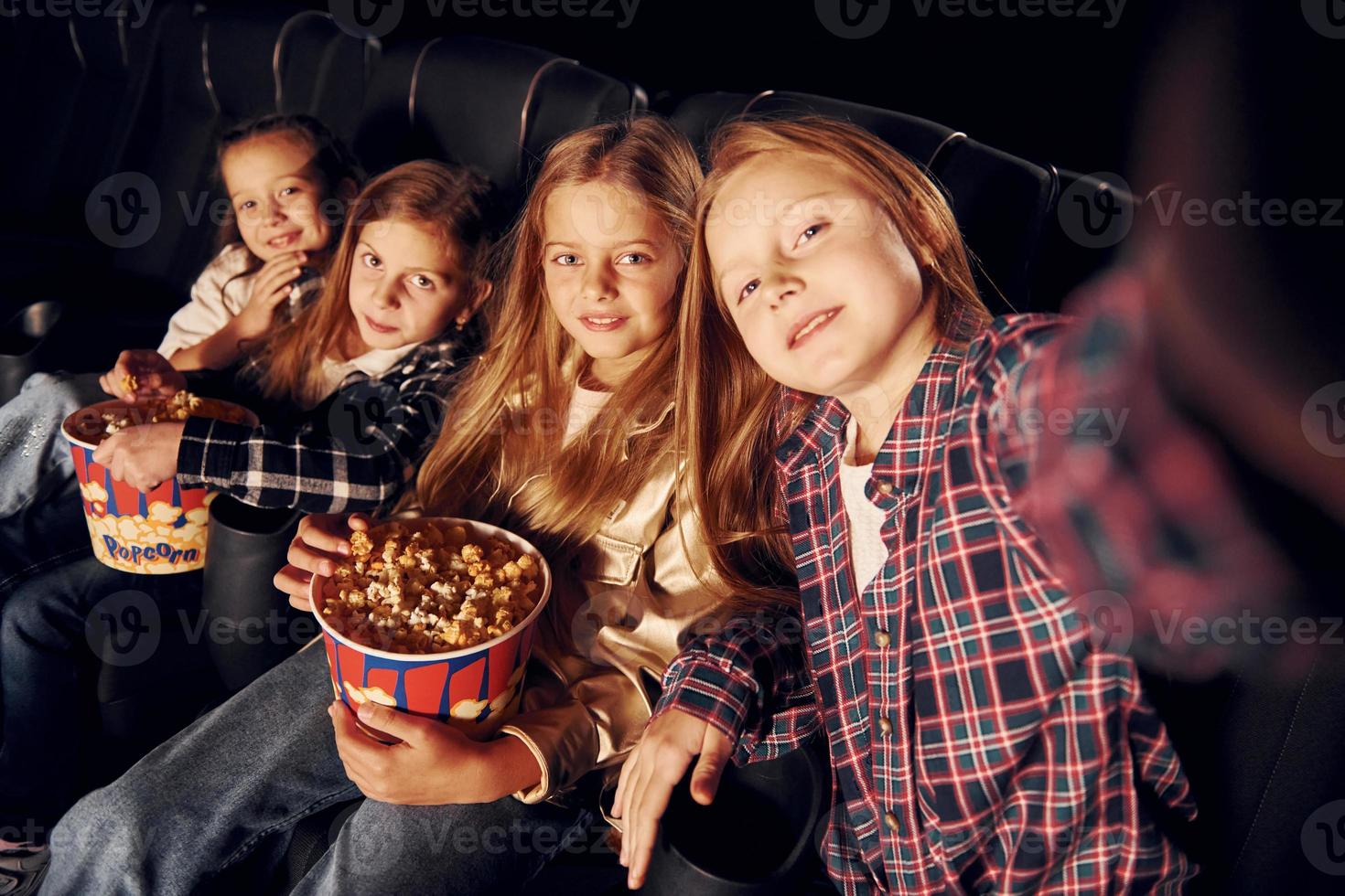 em quarto escuro. grupo de crianças sentadas no cinema e assistindo filme juntos foto