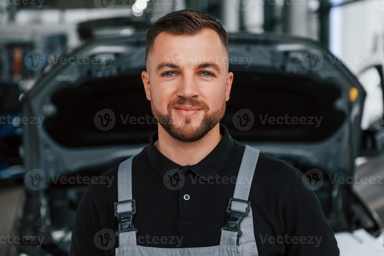 de pé contra o carro. homem de uniforme está trabalhando no autosalon durante o dia foto