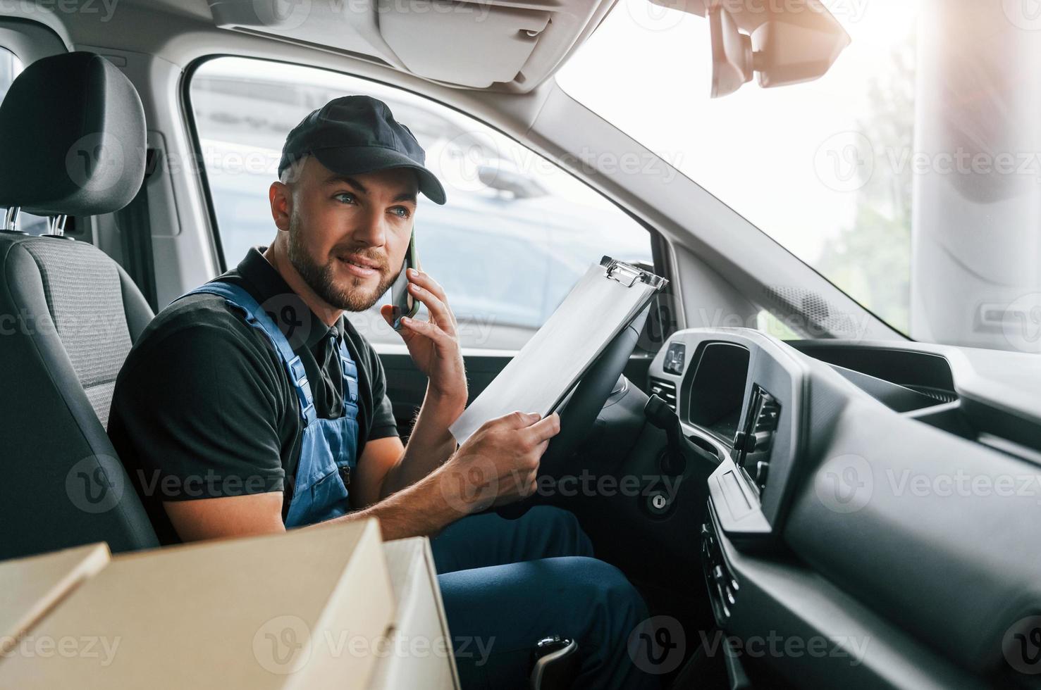 veículo moderno. entregador de uniforme está dentro de casa com carro e com pedido foto