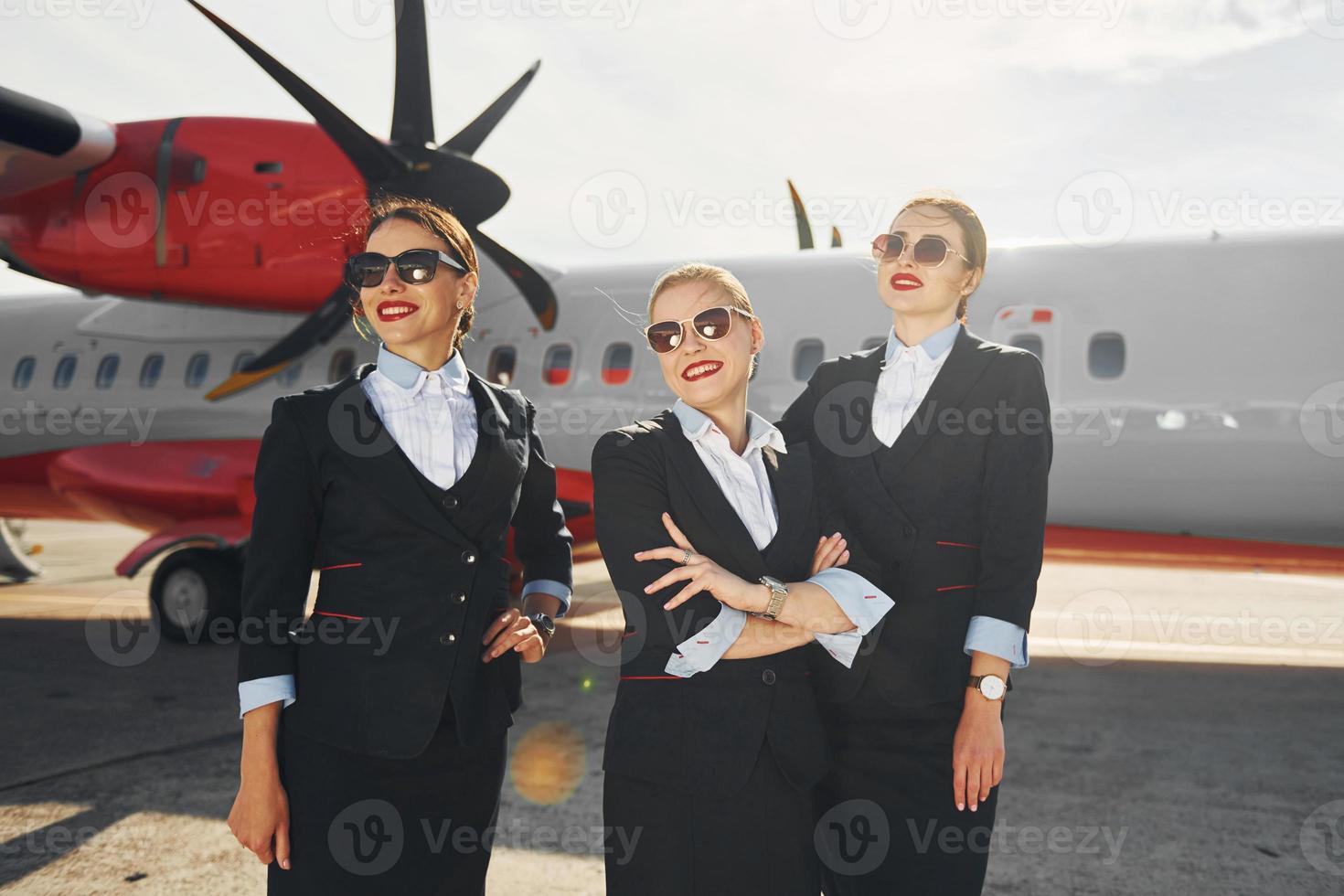 três pessoas. tripulação de trabalhadores do aeroporto e avião em roupas formais juntos ao ar livre foto