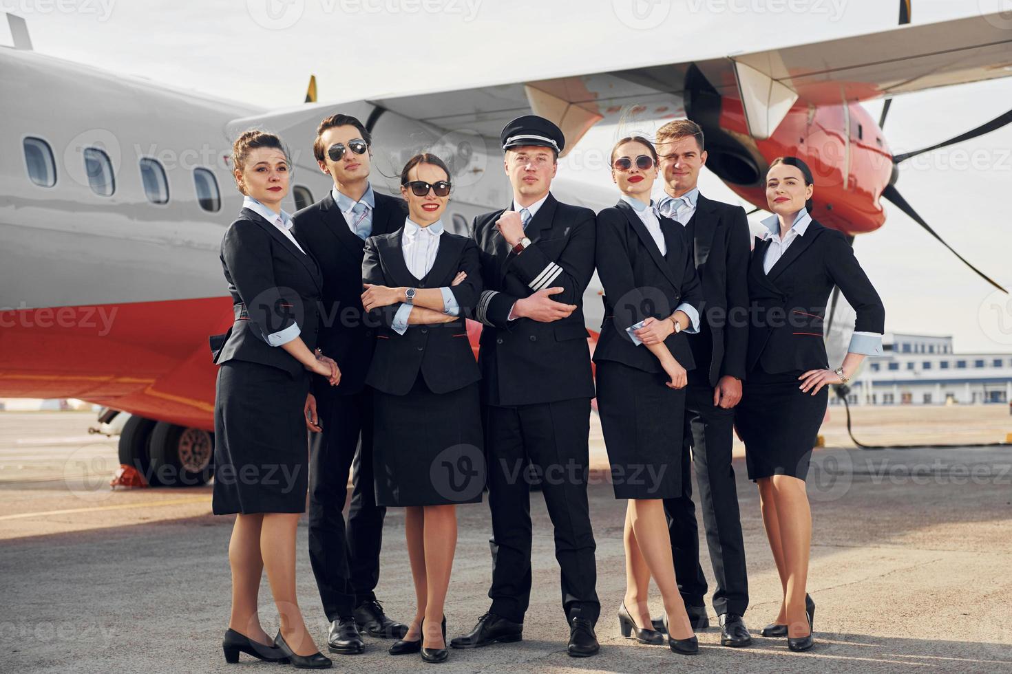 posando para uma câmera. tripulação de trabalhadores do aeroporto e avião em roupas formais juntos ao ar livre foto