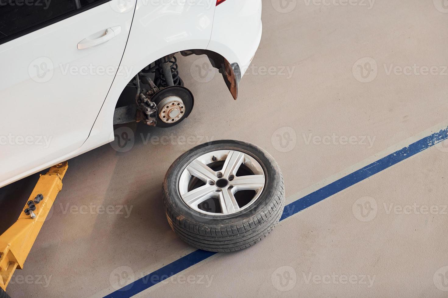 roda de carro deitada perto do automóvel. concepção de reparação foto