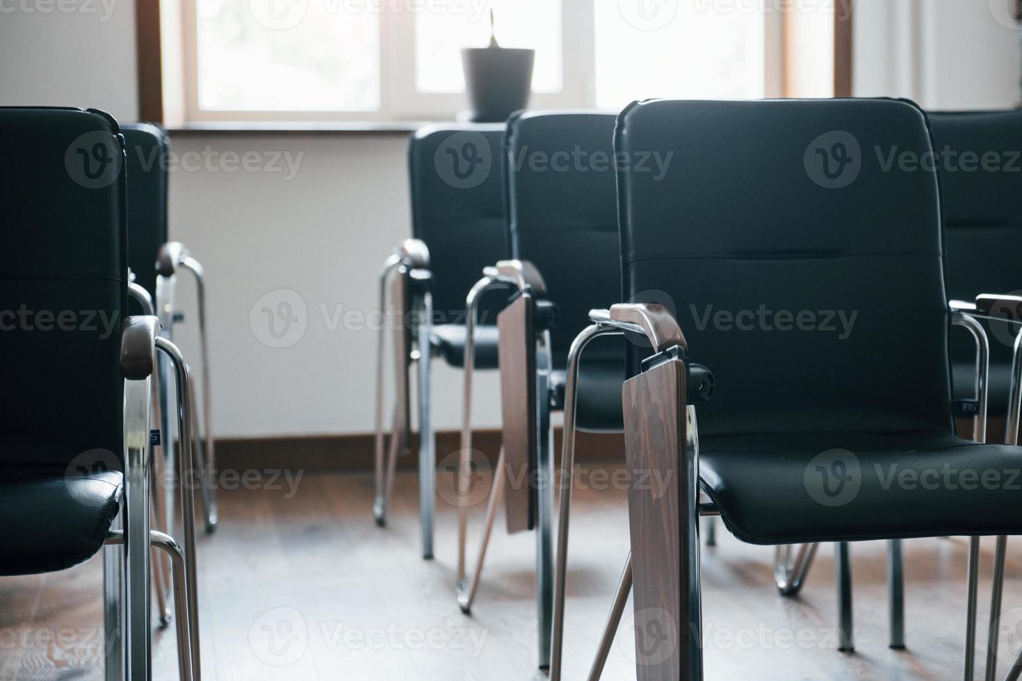 iluminação natural. sala de aula de negócios durante o dia com muitas cadeiras pretas. pronto para estudantes foto