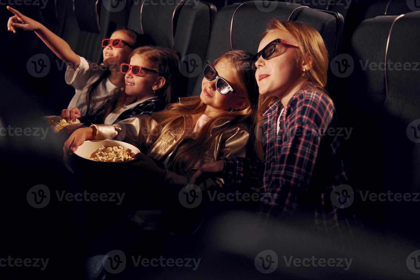 em óculos 3d. grupo de crianças sentadas no cinema e assistindo filme juntos foto