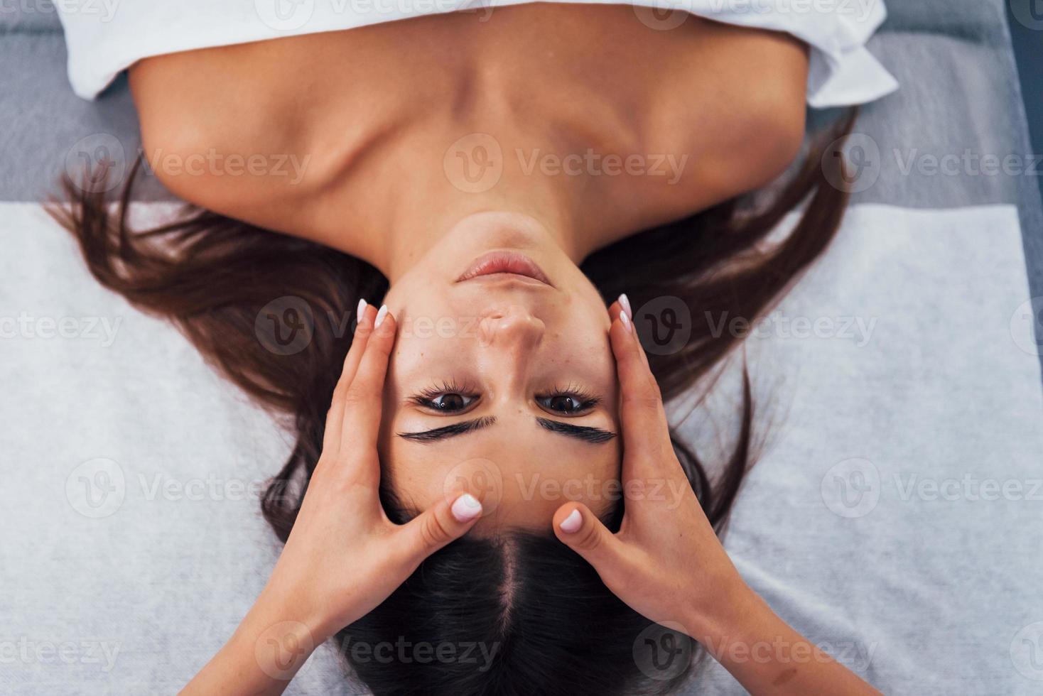 close-up vista da mulher que está deitada no salão spa e tem massagem facial foto