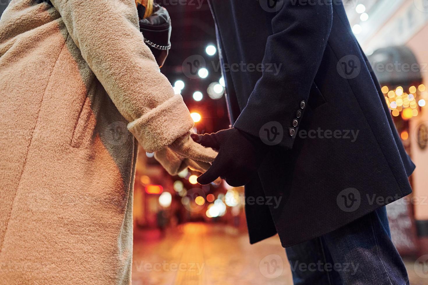 close-up vista do jovem casal em roupas quentes que está na rua decorada de natal juntos foto