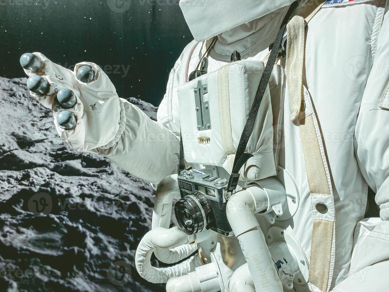 terno branco com astronauta de traje espacial no espaço. ele tem uma câmera pendurada no pescoço. no terno de um tubo para garantir a respiração do astronauta foto