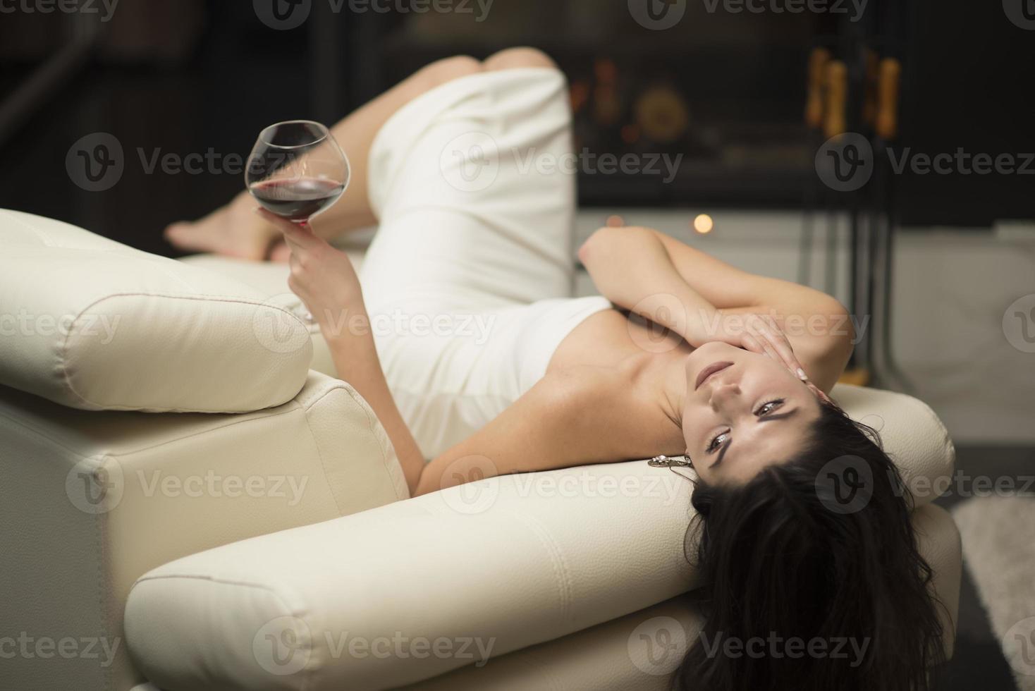morena atraente bebendo vinho perto de uma lareira foto
