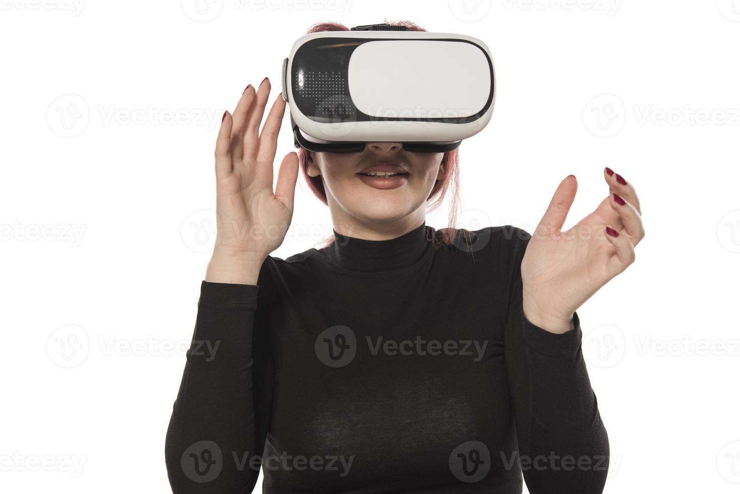 mulher muito bonita animada no fone de ouvido vr olhando para cima e tentando tocar objetos na realidade virtual foto