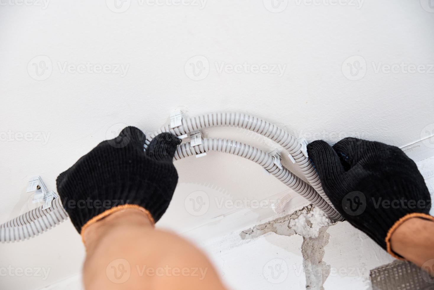 eletricista fixando o cabo elétrico na parede, closeup foto
