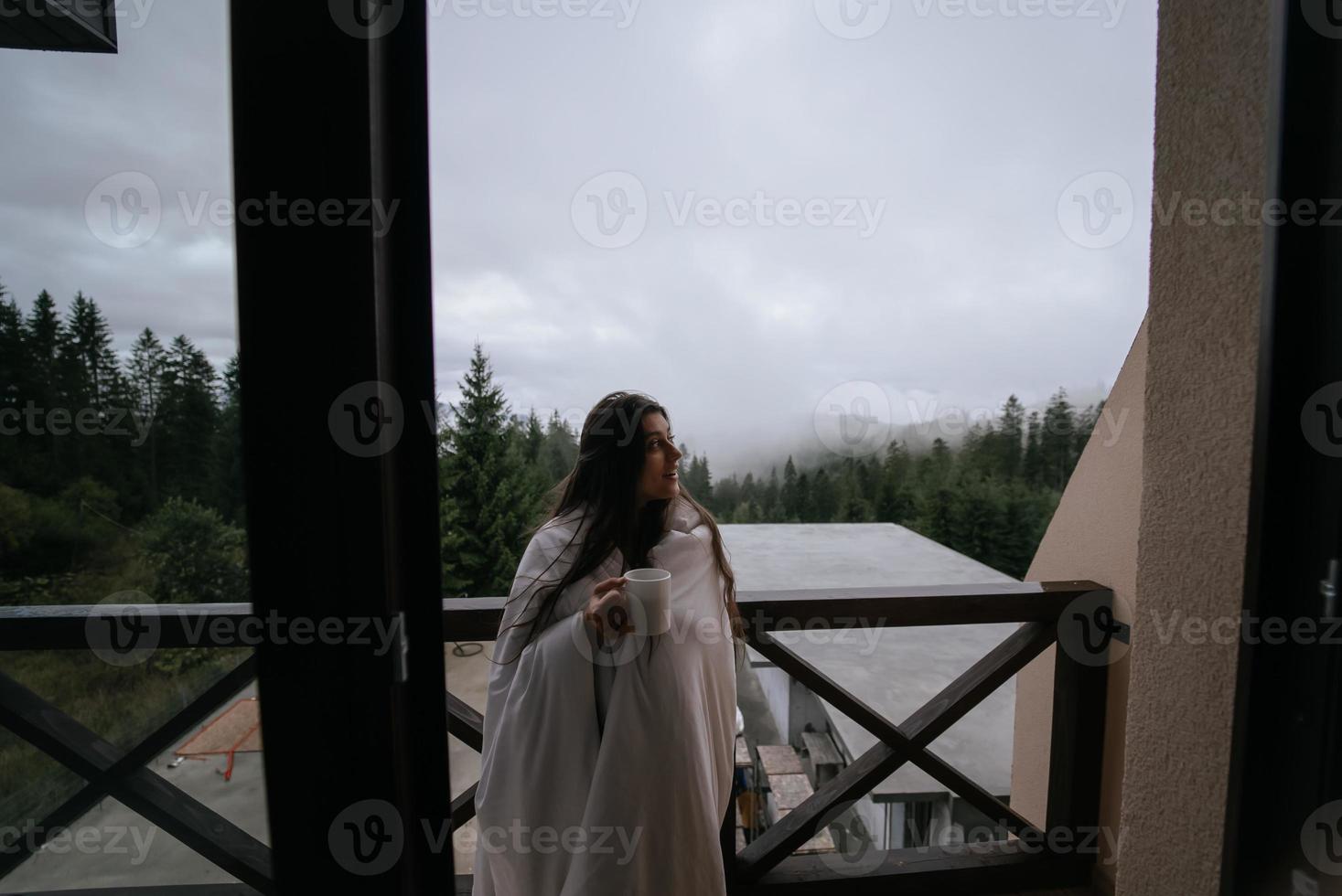 mulher bebendo chá na aconchegante varanda de uma casa de campo. foto