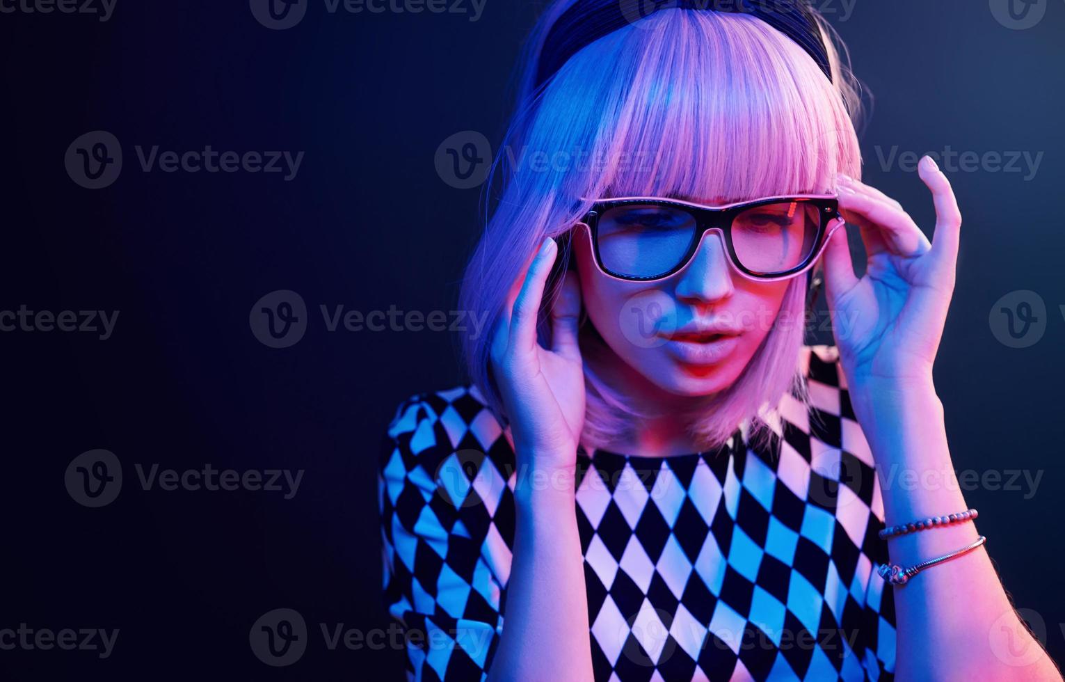 retrato de jovem com cabelo loiro em óculos em néon vermelho e azul no estúdio foto