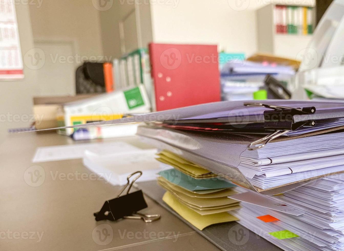 artigos de papelaria em cima da mesa no escritório. pastas com papéis, documentos para trabalho de escritório. sobre a mesa estão folhas adesivas e clipes de papel foto