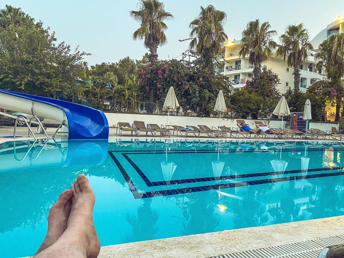 férias no mar na praia. turista tomando banho de sol em uma espreguiçadeira à beira da piscina. pernas masculinas brancas. relaxamento, férias em um país quente tropical foto