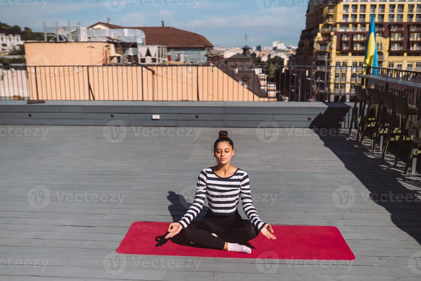 jovem meditando em pose de lótus no telhado do edifício foto