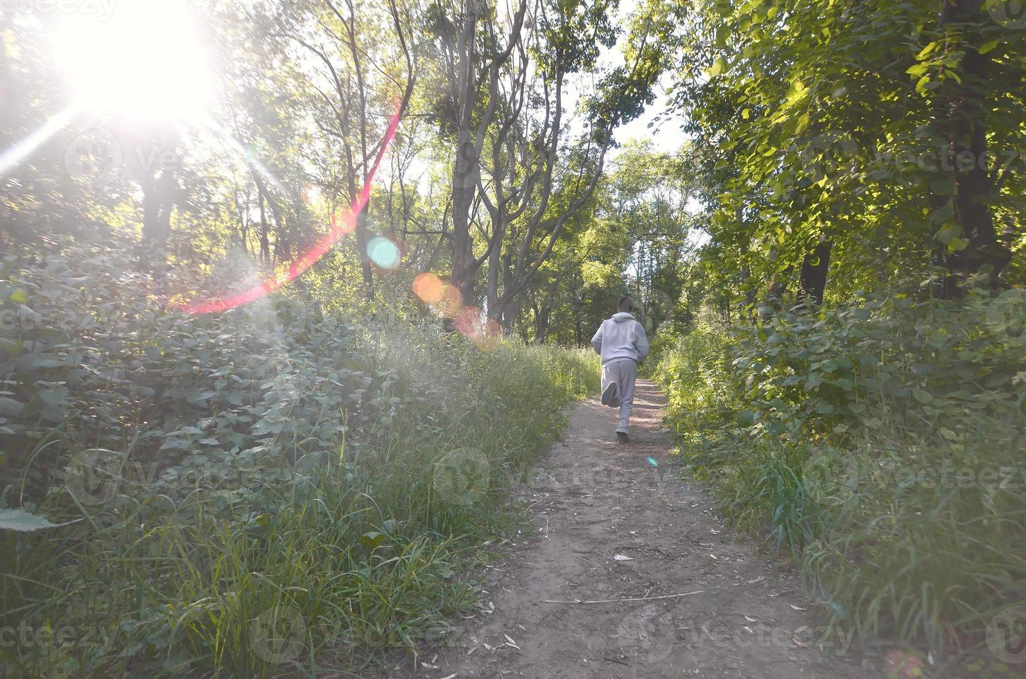 um jovem em um terno esportivo cinza corre ao longo do caminho entre os foto