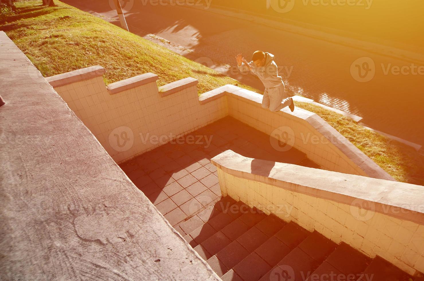 um jovem dá um salto pelo espaço entre os parapeitos de concreto. o atleta pratica parkour, treinando em condições de rua. o conceito de subculturas esportivas entre os jovens foto