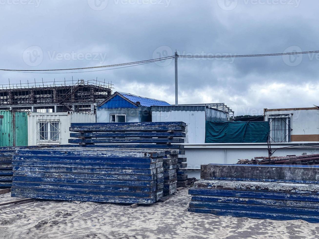 canteiro de obras de um complexo industrial. varas azuis empilhadas juntas. material de construção no contexto de pequenas casas onde vivem os construtores foto