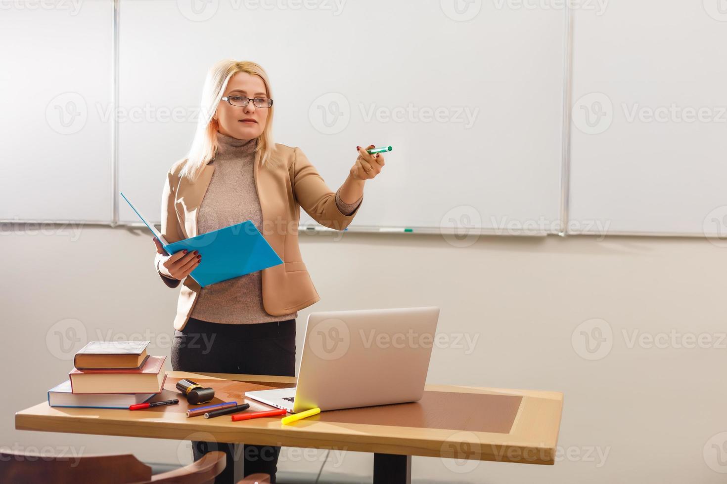 retrato de professora bonita segurando blocos de notas em uma sala de aula na escola foto