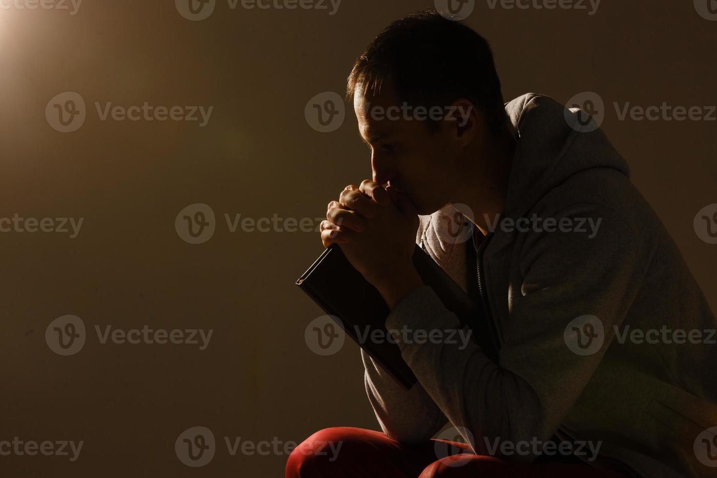 jovem religioso orando a deus em fundo escuro, efeito preto e branco foto