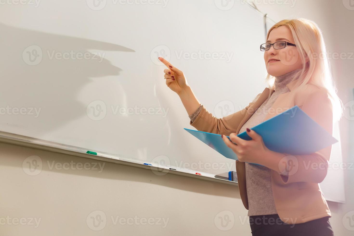 retrato de professora bonita segurando blocos de notas em uma sala de aula na escola foto