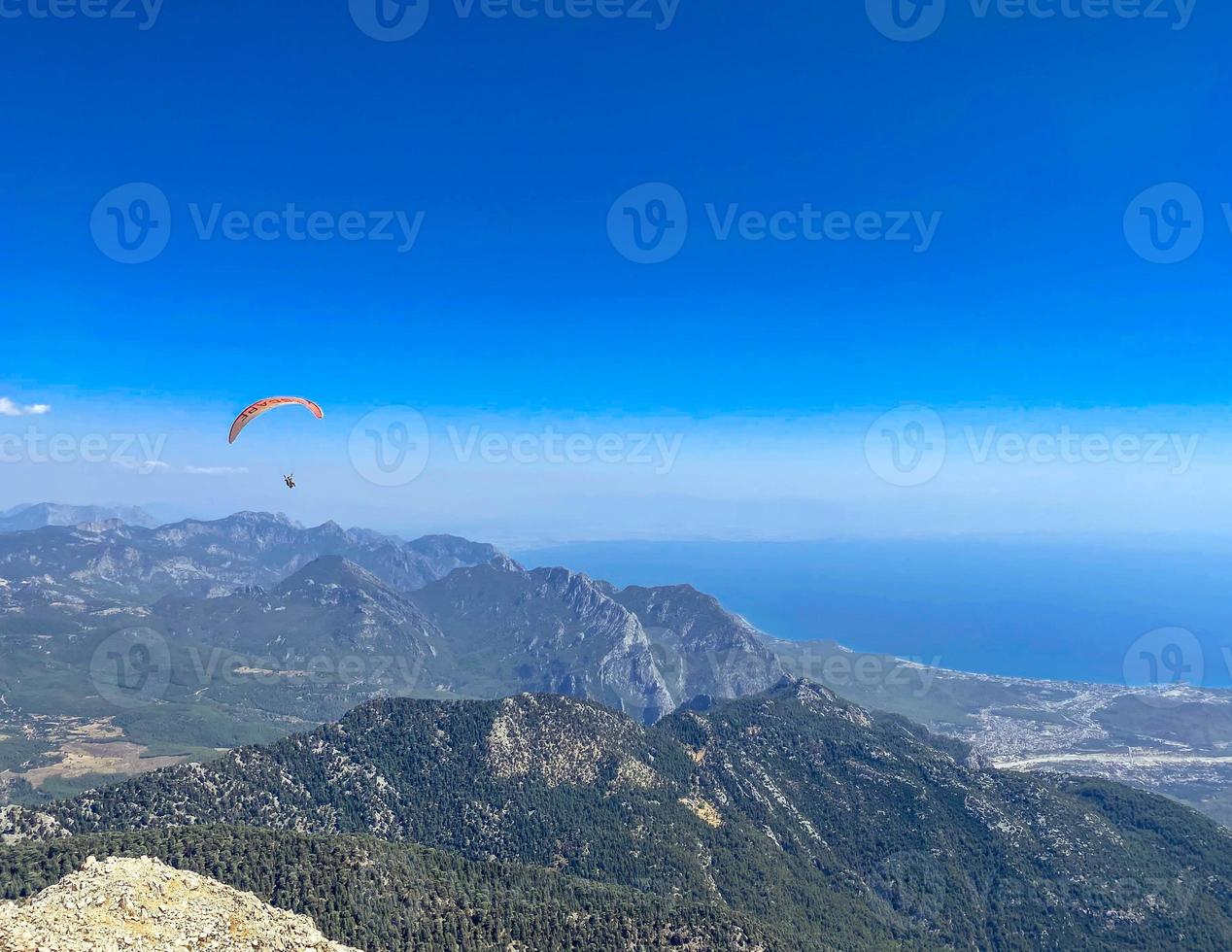 pára-quedistas voam pelo ar. saltar para baixo em um parapente. vista da cidade de uma altura de vôo. parapente com vista para a montanha foto