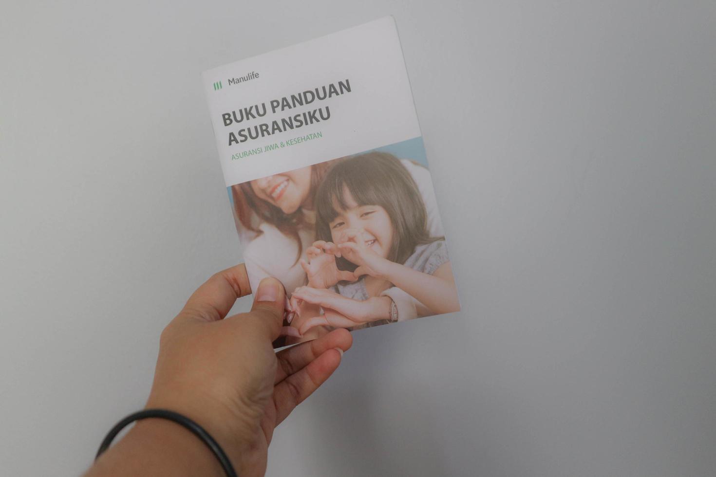 java ocidental, indonésia em julho de 2022. uma mão segurando o manual de seguro da manulife para seguro de vida e saúde foto