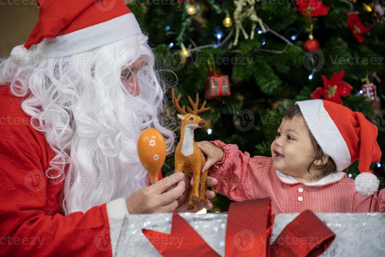 bebê caucasiano está recebendo presente do papai noel à noite pela árvore  de natal totalmente decorada para o conceito de celebração da temporada  15586262 Foto de stock no Vecteezy
