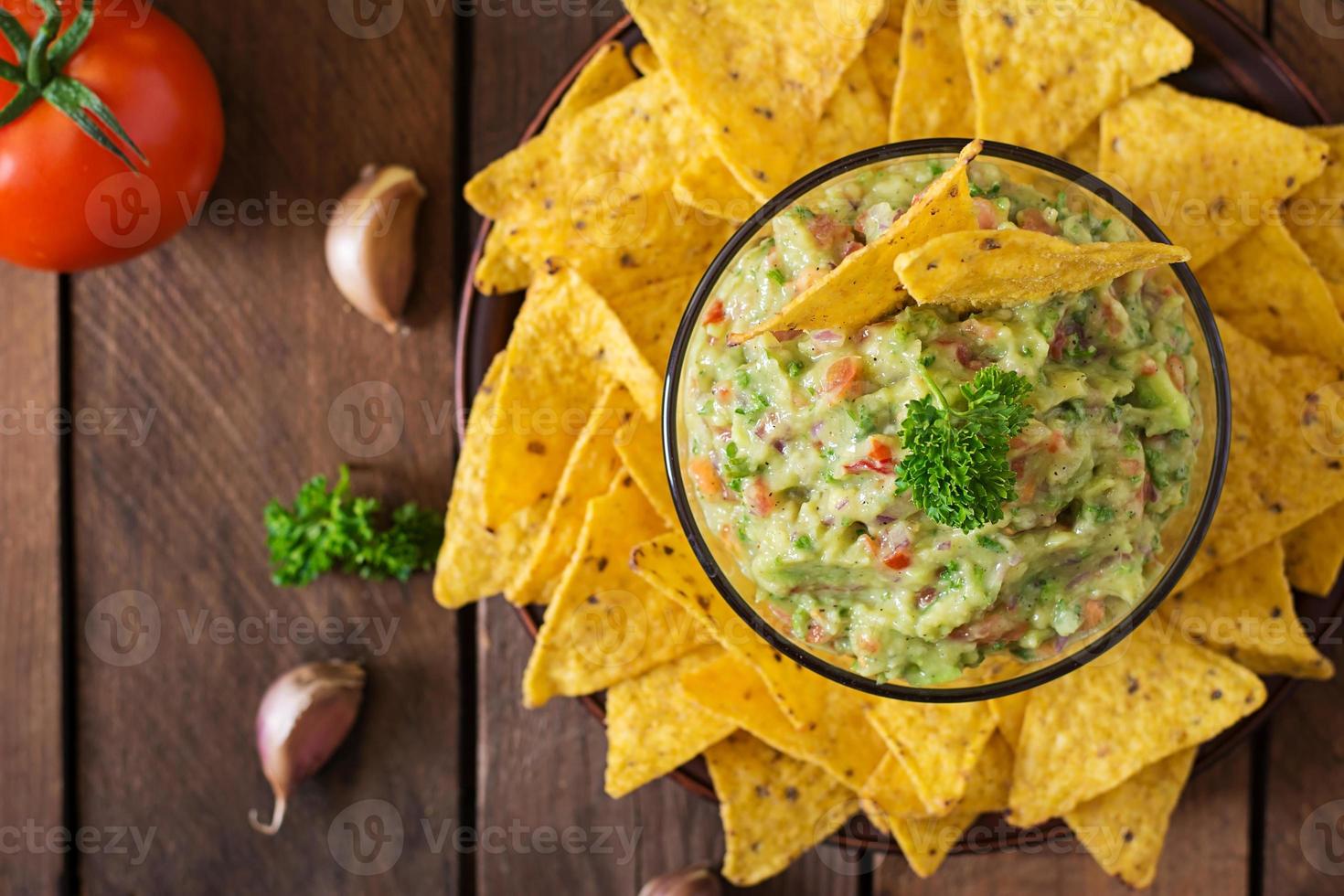 abacate guacamole, limão, tomate, cebola e coentro, servido com nachos - lanche mexicano tradicional foto