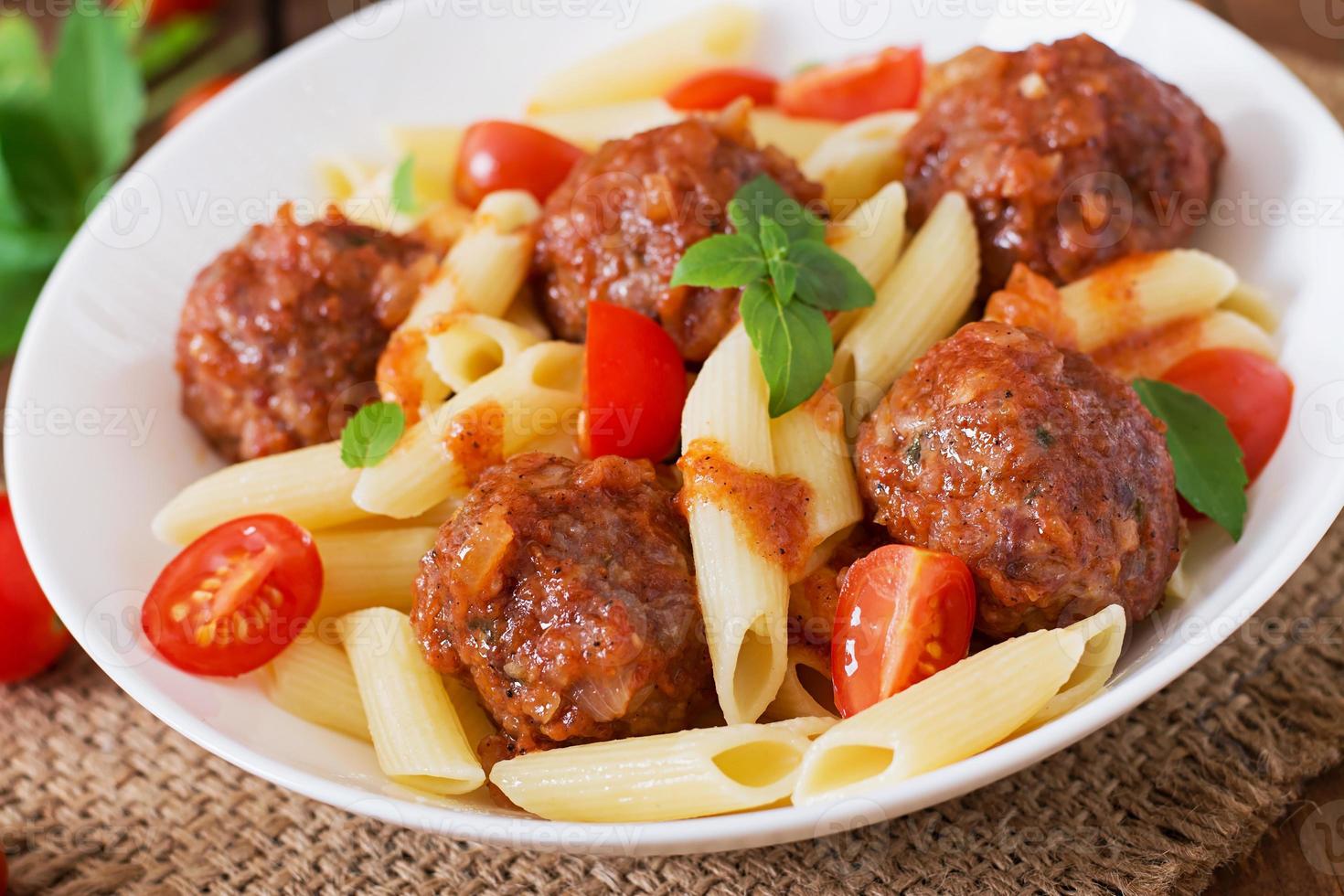 macarrão penne com almôndegas em molho de tomate em uma tigela branca foto