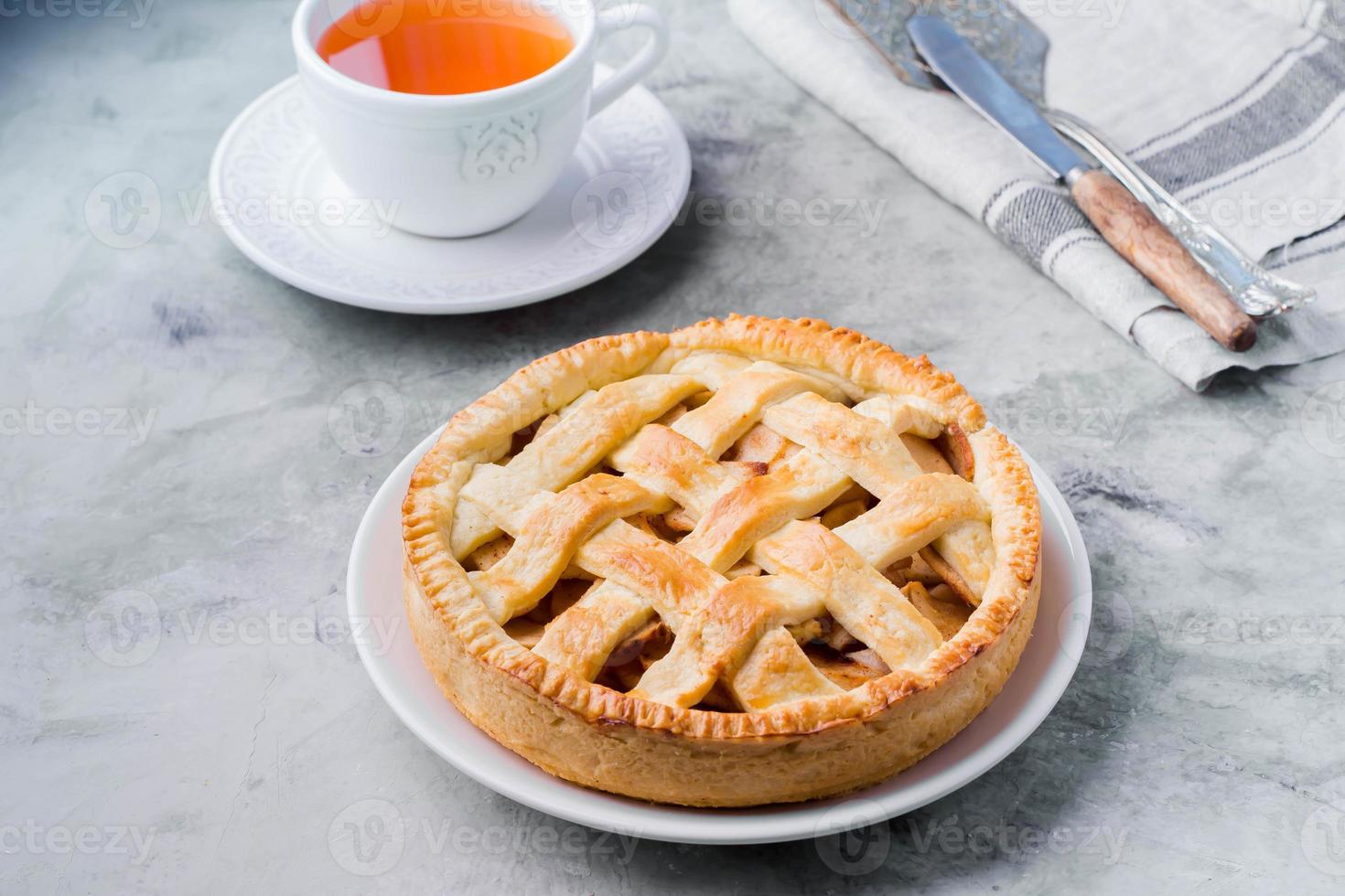 torta de maçã americana popular e xícara de chá na mesa cinza. torta de frutas clássica caseira. copie o espaço foto