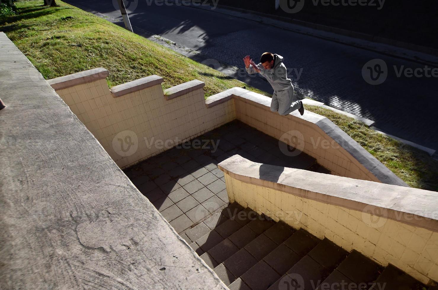 um jovem dá um salto pelo espaço entre os parapeitos de concreto. o atleta pratica parkour, treinando em condições de rua. o conceito de subculturas esportivas entre os jovens foto